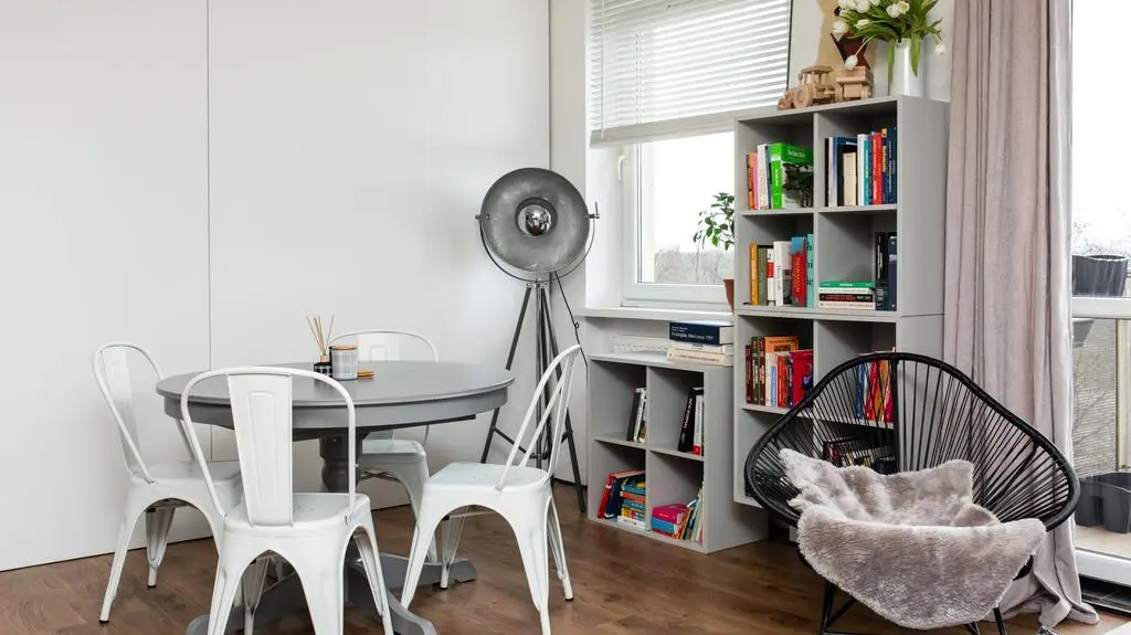 Modna lampa nawiązująca do dawnych lamp fotograficznych i metalowe krzesła żywcem wyjęte z kawiarnianych ogródków dodają wnętrzu nowoczesnego stylu.