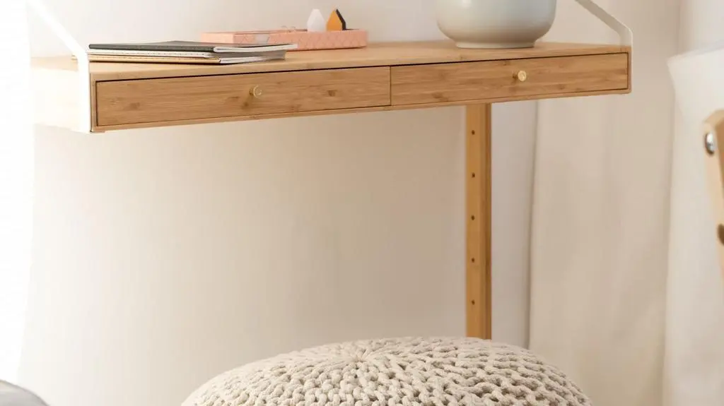 Pod biurkiem stanął puf w beżowym kolorze.