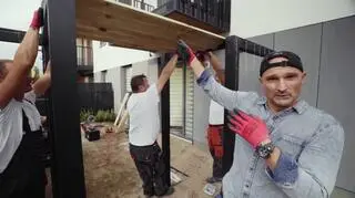 W ogrodzie Rafała i Andrieja brakowało miejsca do relaksu. Dominik Strzelec postanowił więc zrobić dla nich aż dwa takie miejsca, w formie bliźniaczych konstrukcji z drewna. Tarasy zostały obudowane czterema filarami połączonymi nietypowym dachem w formie żaluzji.  Przepuszcza on światło, a jednocześnie chroni przed wścibskim wzrokiem sąsiadów. Pomalowane na szaro konstrukcje zostały wzbogacone o kratkę na bluszcz, który już wkrótce porośnie jej boki, tworząc na tarasie przytulny i intymny klimat.