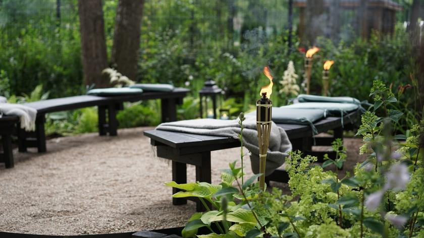 Mimo prób pani Ani nie udawało się zagospodarować ogródka tak, jak to sobie wymarzyła. Problemem było ograniczone przez położenie działki i rosnące na niej drzewa światło słoneczne docierające do roślin. Dominik Strzelec zasadził tam więc rośliny niepotrzebujące dużo światła, które świetnie poradzą sobie w półcieniu i nadadzą ogródkowi leśnego charakteru. Teraz będzie można tam zrelaksować się na ręcznie wykonanych ławach i na patio otoczonym roślinami. Leśny klimat ogródka na pewno sprawi, że i harcerze będą chętnie przychodzić tu na zbiórki.